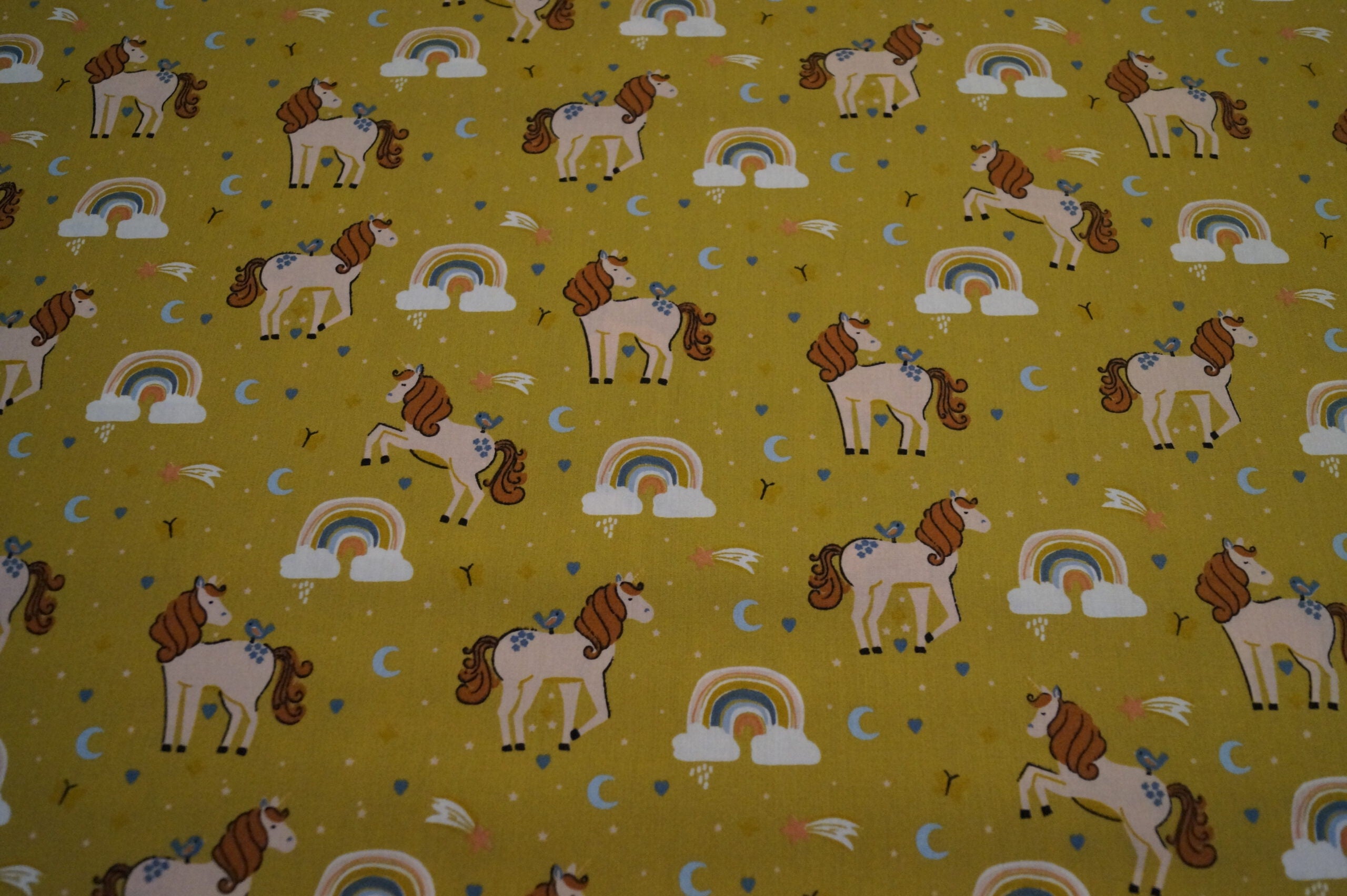 Popeline ockerfarben mit Einhörnern und Regenbogen